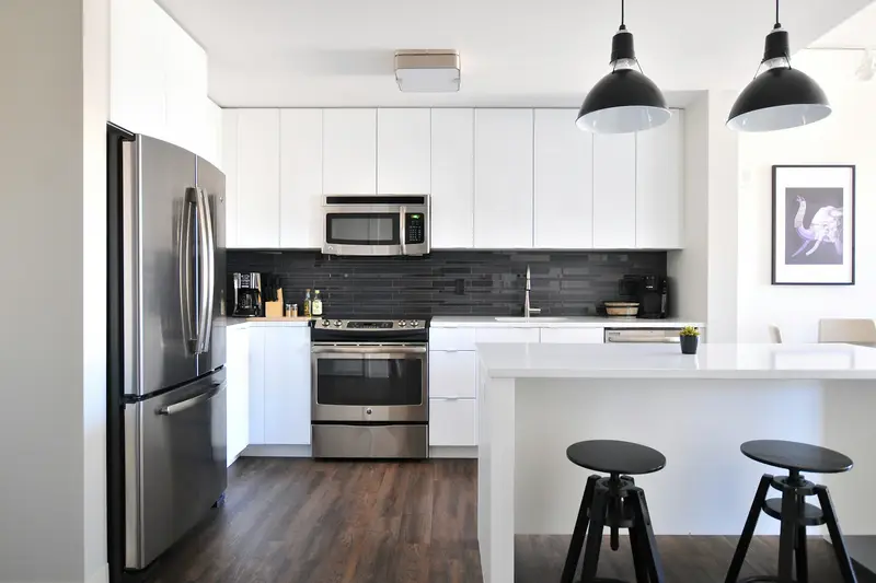 A white kitchen with a stainless French-door refrigerator, a range with an oven, an over-the-range microwave and a built-in dishwasher