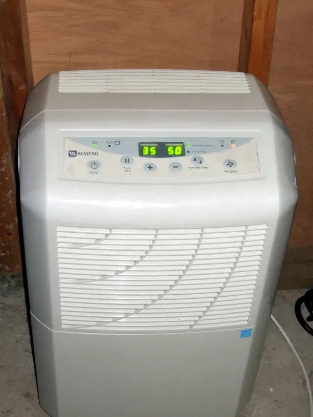 A white portable dehumidifier on a concrete floor, its display set to 35 percent humidity