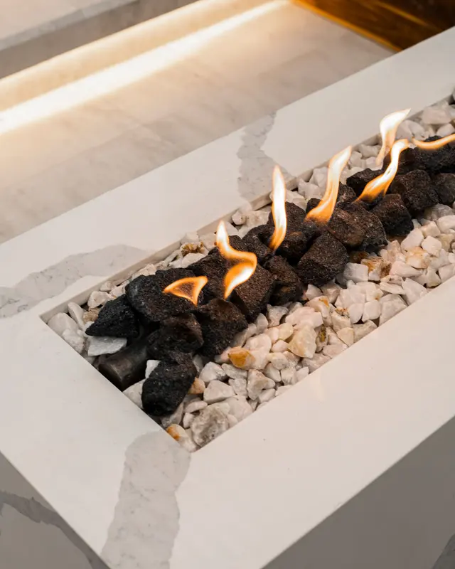 Close-up of a modern gas fireplace with flames rising through a bed of decorative glass stones behind a sealed front