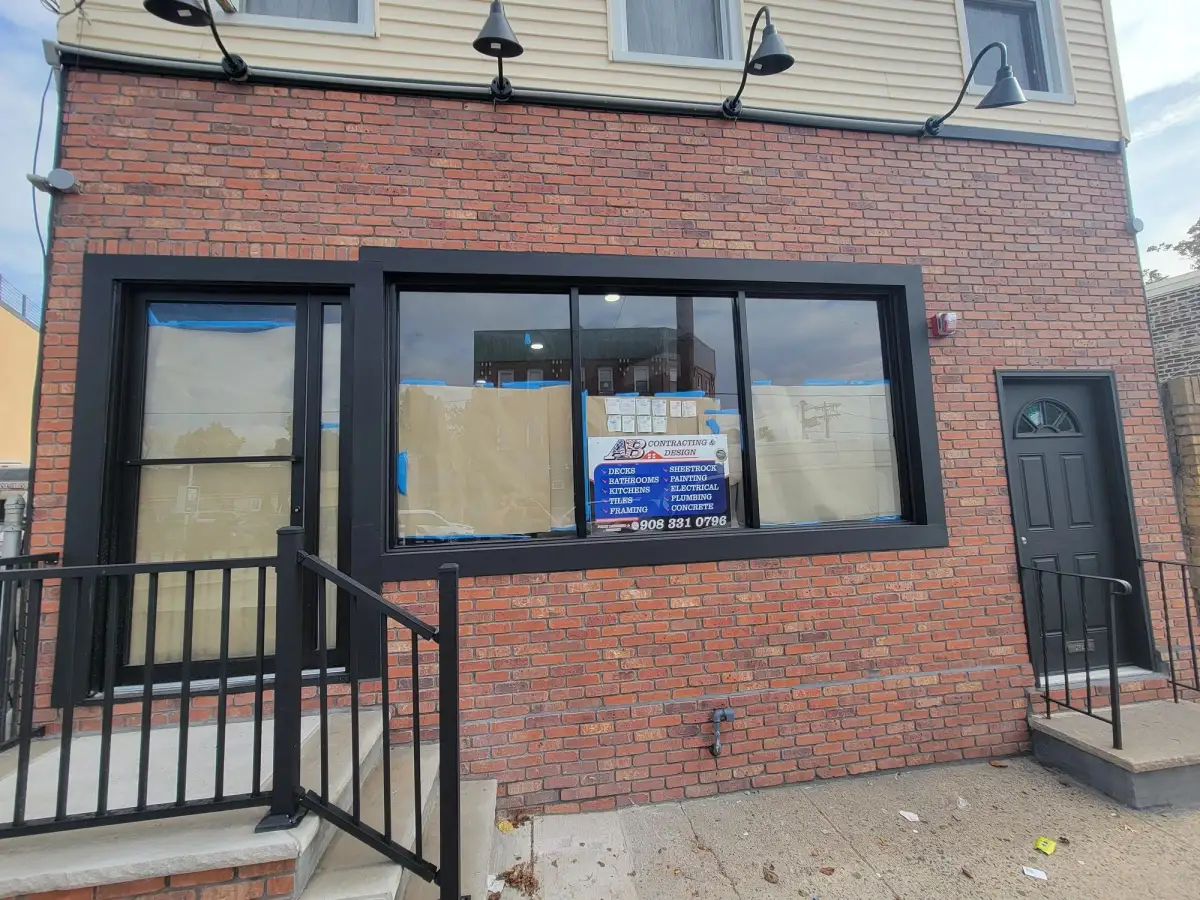 Brick restaurant storefront after renovation, with black-framed windows and an entry door