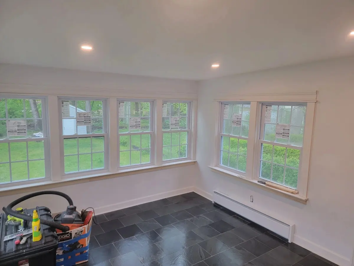 Former enclosed porch finished as a room with a wall of windows, white trim and a slate-look tile floor
